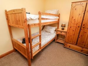 a bedroom with two bunk beds and a night stand at Old Byre Cottage in Ravenstonedale