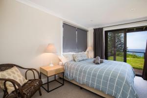 a bedroom with a bed and a chair and a window at Seaview I Pet Friendly with Stunning Views I 1 Min to Beach in Culburra Beach