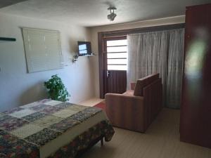 a bedroom with a bed and a chair and a window at Sossego do Interior II in Nova Petrópolis