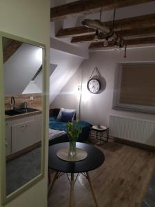 a living room with a table and a clock on the wall at Apartament Kala in Nysa