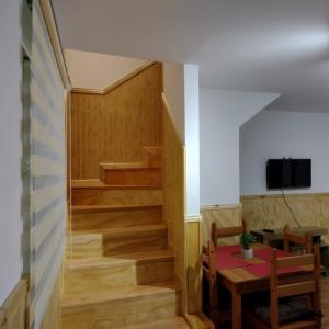 Habitación con mesa y escalera con TV. en Departamentos Kitkaika, en Punta Arenas