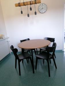 a wooden table with chairs and a clock on the wall at Apartament Leśny in Szczejkowice