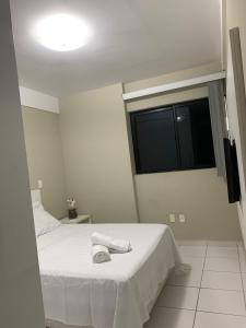 1 dormitorio con cama blanca y ventana en Apartamento em Maceió en Maceió