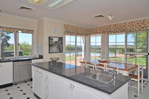 a kitchen with a sink and a table and some windows at Beggars Bridge Vineyard Homestead with pool and tennis in Rothbury