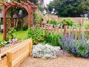 Virginia Cottage في Bulwick: سور خشبي في حديقة بها زهور أرجوانية وبيضاء