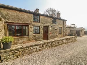 an old stone house with a stone wall at Stable Cottage in Kirkby Stephen