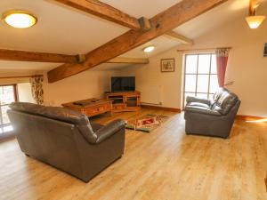 sala de estar con 2 sillas de cuero y TV en Stable Cottage en Kirkby Stephen