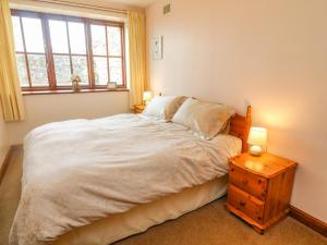 a bedroom with a bed and a night stand with two lamps at Stable Cottage in Kirkby Stephen