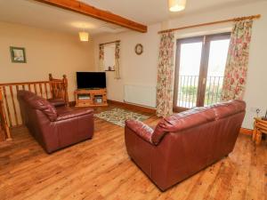 sala de estar con 2 sillas de cuero y TV en Hayloft Cottage, en Kirkby Stephen