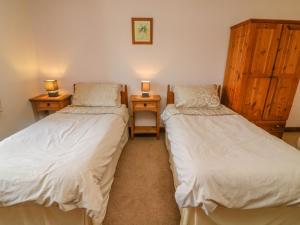 カークビー・ステファンにあるHayloft Cottageのベッド2台、ランプ2つ(テーブル付)が備わる客室です。