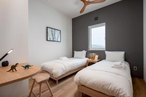 a bedroom with two beds and a desk and a table at Kaku Place by H2 Life in Furano