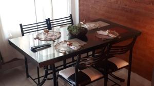 a glass table with four chairs and plates and a remote at Ensueños in Trelew