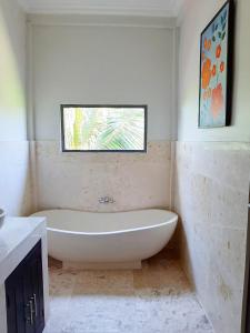 a bathroom with a bath tub and a window at Medewi Manor in Airsatang