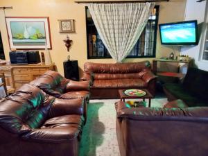 Sala de estar con 2 sofás de cuero y TV en Casa Campestre La Colombiana, en Montenegro