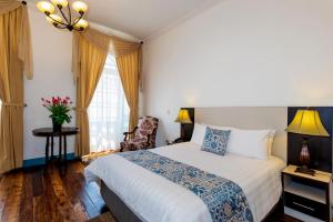 a bedroom with a bed and a chair and a window at Del Parque Hotel & Suites in Cuenca