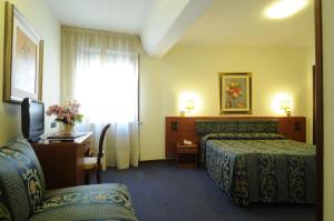 a hotel room with two beds and a desk and a window at Hotel Cristallo in Conegliano