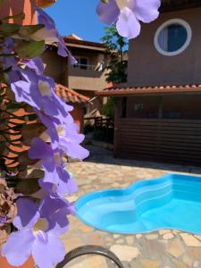 uma piscina com flores roxas ao lado de uma casa em Sol Mar na Praia do Rosa