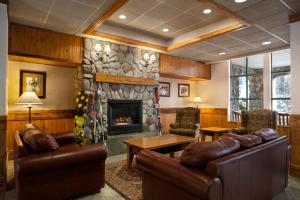 a living room with leather furniture and a stone fireplace at Sundance Lodge in Sun Peaks