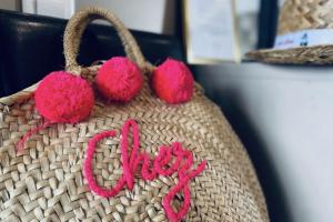 a woven bag with pink pompoms on it at Le Château Leenhardt in Le Grau-du-Roi