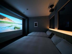 Zimmer mit einem TV und einem Bett in einem Zimmer in der Unterkunft Rakuten STAY naha-tomarifuto 1F Twin Room in Naha