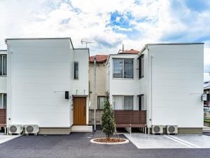 zwei weiße Häuser mit einem Baum auf einem Parkplatz in der Unterkunft Rakuten STAY HOUSE x WILL STYLE Takasaki 105 in Takasaki