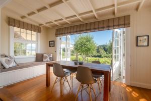 a dining room with a table and chairs and a window at Kina Beach Cottages in Tasman