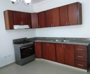 a kitchen with wooden cabinets and a sink and a stove at Bright Apartment at Punta Cana WIFIAcElectIronParking in Punta Cana