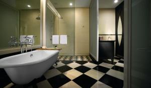 a bathroom with a white tub and a checkered floor at Eastern & Oriental Hotel in George Town