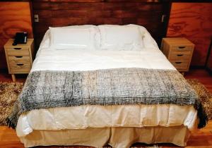 un letto con lenzuola e cuscini bianchi in una camera da letto di Hotel Aliwen a Dalcahue