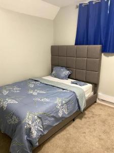 a bed in a bedroom with a blue curtain at Beautiful and Spacious 1 room in a very quiet area in Airdrie