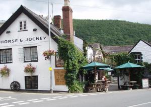 un edificio blanco con mesas y sombrillas en una calle en The Horse & Jockey Inn en Knighton