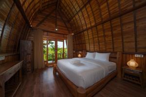 a bedroom with a bed in a wooden room at Ring Sun Cottages in Uluwatu