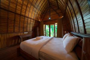 a bedroom with a bed in a wooden room at Ring Sun Cottages in Uluwatu
