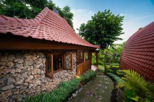 a stone building with a red roof and a pathway at Ring Sun Cottages in Uluwatu