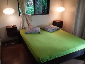 ein Schlafzimmer mit einem grünen Bett mit zwei Kissen in der Unterkunft ROYAL VAI in Faaa