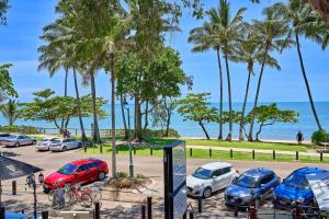 een parkeerplaats met auto's geparkeerd naast het strand bij Alassio Beachfront Apartments Palm Cove in Palm Cove