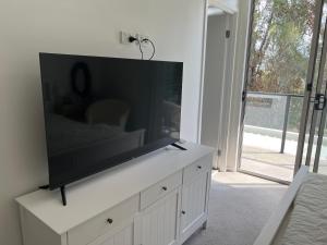 a flat screen tv on a white cabinet in a living room at Superstar’s home stay in Gold Coast