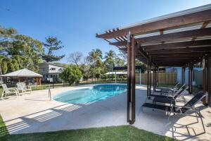 a pool with a pergola and chairs next to a house at Kooyong Apartment 7 in Arcadia