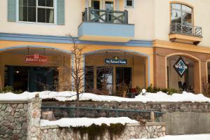 a building with snow on the ground in front of it at Sundance Lodge in Sun Peaks
