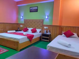1 dormitorio con 2 camas y paredes rojas y verdes en The Lachung Inn, en Lachung