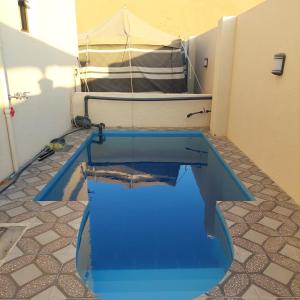 a blue swimming pool in a room with a tent at شاليهات رمال بديه in Al Raka