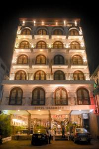 un grande edificio bianco con macchine parcheggiate di fronte di Hotel Casamara a Kandy