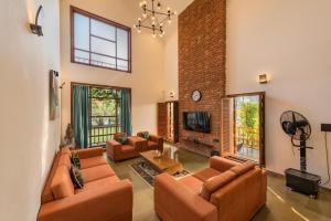 a living room with two couches and a tv at SaffronStays Happy Fields, Pune - luxury farmstay with farm to table food in Pune