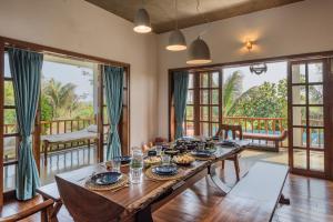 uma sala de jantar com uma mesa de madeira e janelas grandes em SaffronStays Happy Fields, Pune - luxury farmstay with farm to table food em Pune