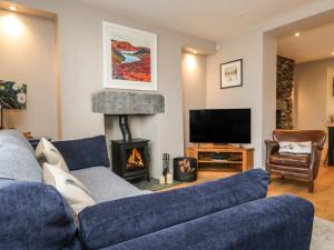a living room with a blue couch and a fireplace at Hugill Cottage in Kendal