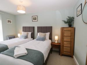 a bedroom with two beds and a dresser with two lamps at Hugill Cottage in Kendal