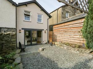 a house with a wooden wall and a patio at Hugill Cottage in Kendal
