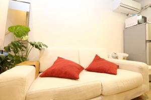 eine weiße Couch mit zwei roten Kissen drauf in der Unterkunft Takemura Building106 in Tokio