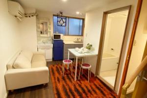 ein Wohnzimmer mit einem Sofa, einem Tisch und einem Stuhl in der Unterkunft Takemura Building106 in Tokio