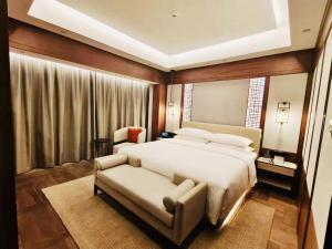 a bedroom with a bed and a couch and a chair at Yidu Jinling Grand Hotel Yancheng in Yancheng